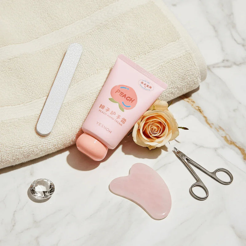 Fruit Fragrance Milky Hand Cream packaging with peach design on marble surface, accompanied by beauty tools and a rose.
