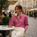 Woman in pink floral shirt enjoying coffee at outdoor café, chic fashion from Ivorynn