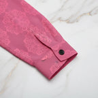 Pink floral shirt cuff with black button on marble surface at Ivorynn
