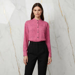 Woman in pink floral shirt and black trousers standing against marble wall, Ivorynn fashion