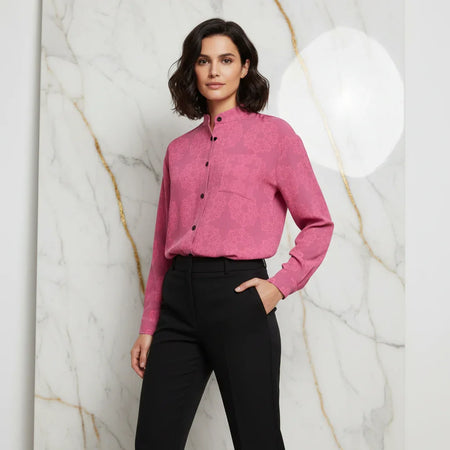 Woman in pink floral shirt and black pants posing against marble wall, stylish women's fashion
