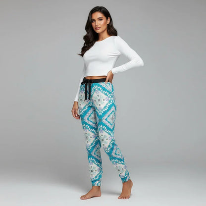 Woman modeling Ivorynn women's fashion, wearing a white long sleeve top and patterned jogger pants, in a studio with a gray backdrop.