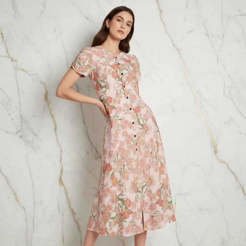 Woman modeling floral pink midi dress against marble wall, stylish women's fashion from Ivorynn