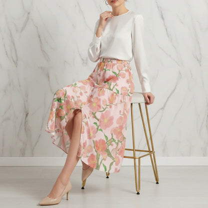 Woman in stylish ivory blouse and pink floral skirt seated on modern stool, Ivorynn fashion