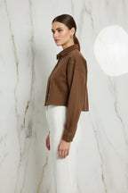 Side profile of brown denim shirt with white pants on marble background