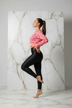 Woman in pink polka dot crop top and black leggings poses in modern studio setting, Ivorynn fashion