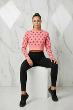 Woman in pink polka dot crop sweatshirt and black leggings sitting, Ivorynn fashion