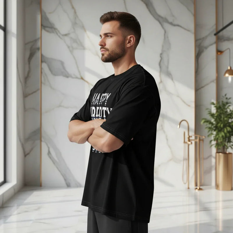 Sporty man in black graphic t-shirt standing in modern marble interior at Ivorynn fashion store