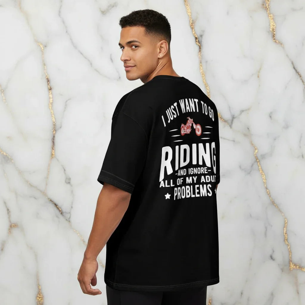 Sporty man wearing a black riding graphic t-shirt, standing in front of marble wall, Ivorynn fashion
