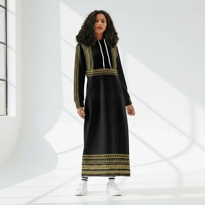 Woman modeling a black and gold long hoodie dress in a sunlit studio for Ivorynn fashion