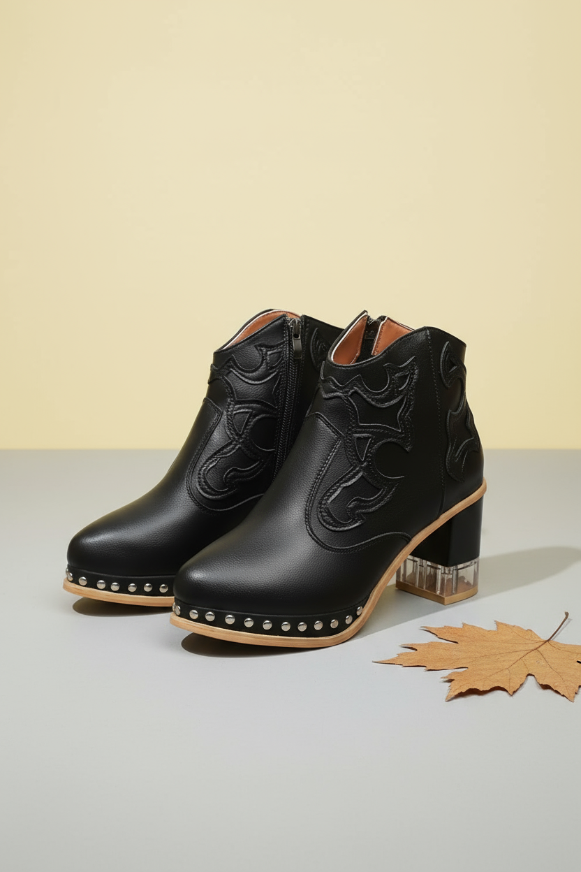 Black ankle boots with decorative patterns and clear heel on a white background