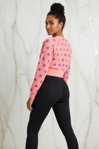 Woman in pink polka dot sweatshirt and black leggings studio shot, Ivorynn fashion