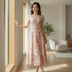 Woman in a floral pink dress standing by a window in a modern living room, Ivorynn fashion