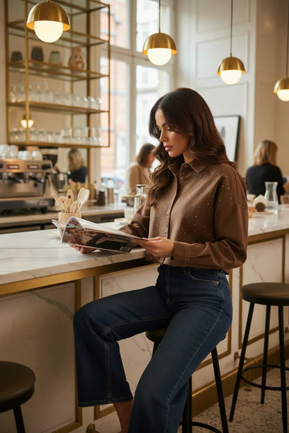 Woman in brown denim shirt with dark jeans at café counter