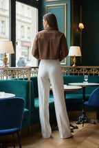 Woman in brown denim shirt with white pants, back view at café